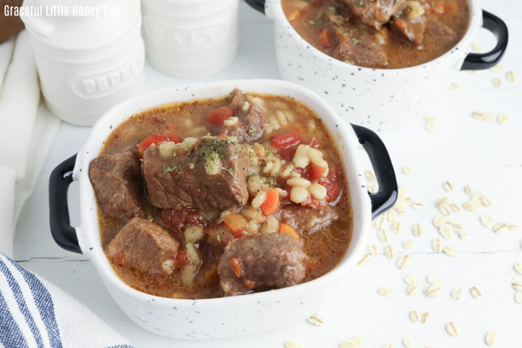 White bowl full of rich, hearty Instant Pot Beef & Barley Stew.